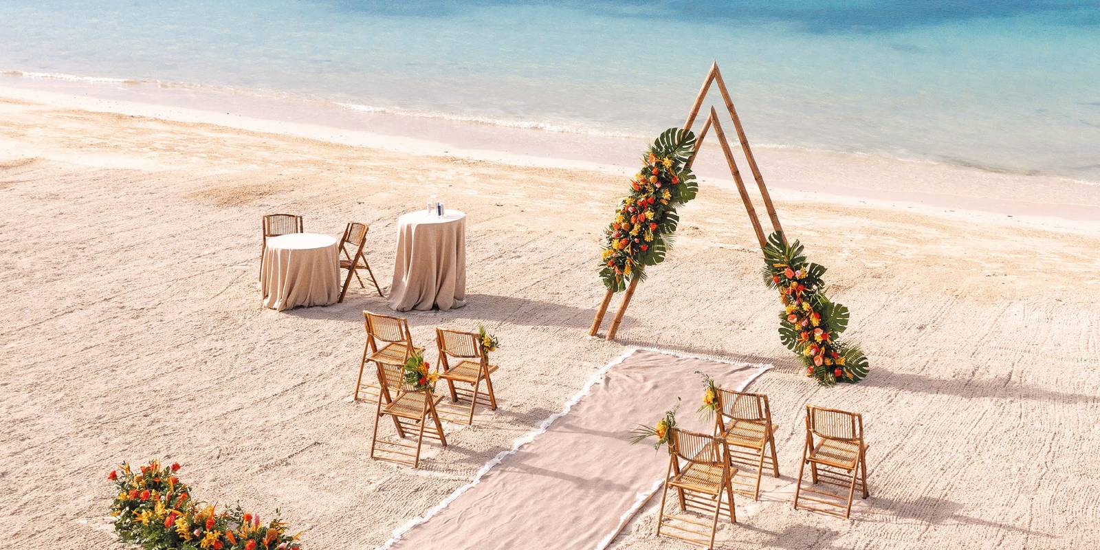 Beachfront wedding ceremony setup with a floral wooden arch on a Sandals beach